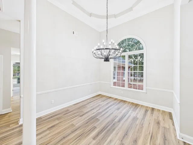 a view of an empty room with wooden floor fridge and a window