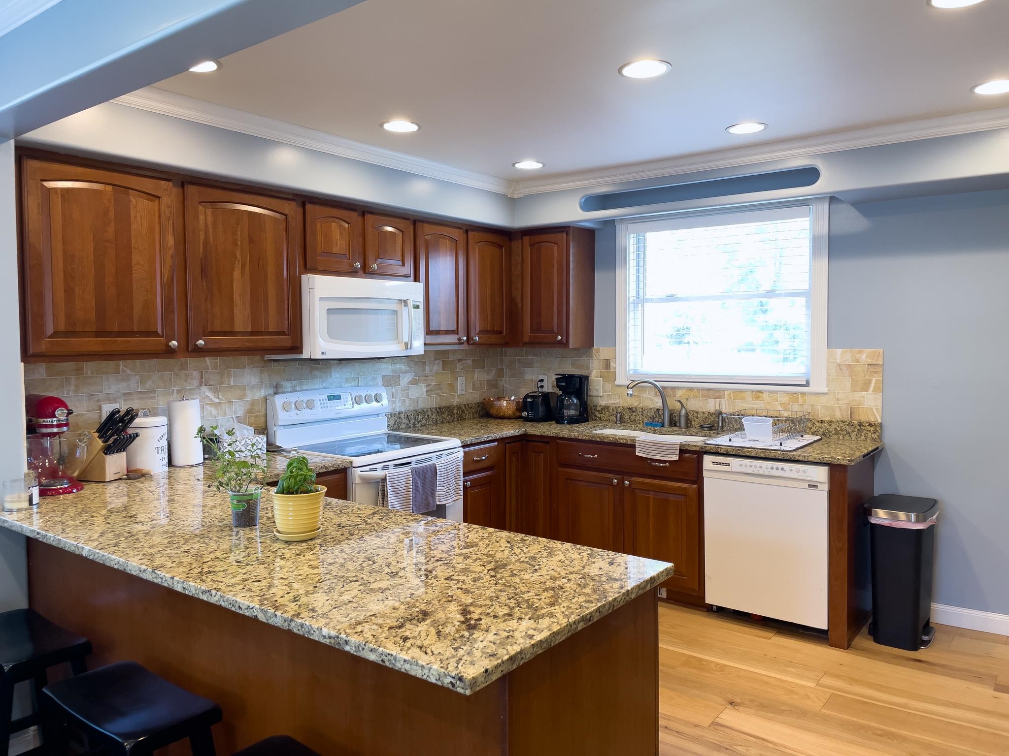 20 Field Road Silver Bay, MN 55614 - Photo 38 of 42 Kitchen featuring white appliances, a peninsula, light stone countertops, a breakfast bar, and ornamental molding