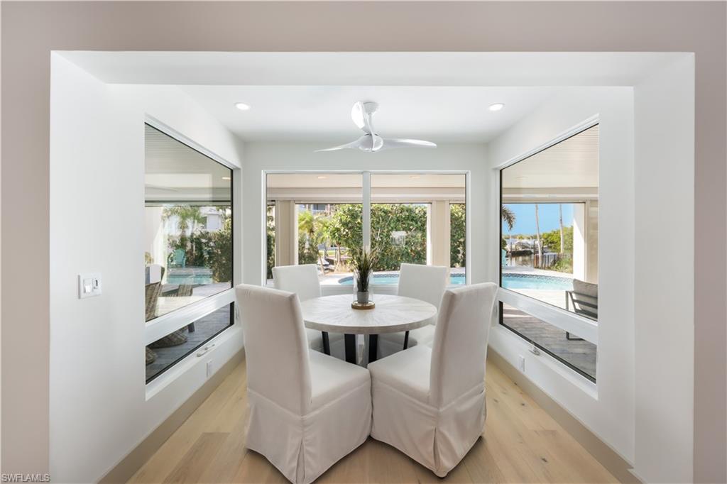 5215 Seashell Avenue Naples, FL 34103 - Photo 13 of 47 a dining room with furniture a chandelier and wooden floor
