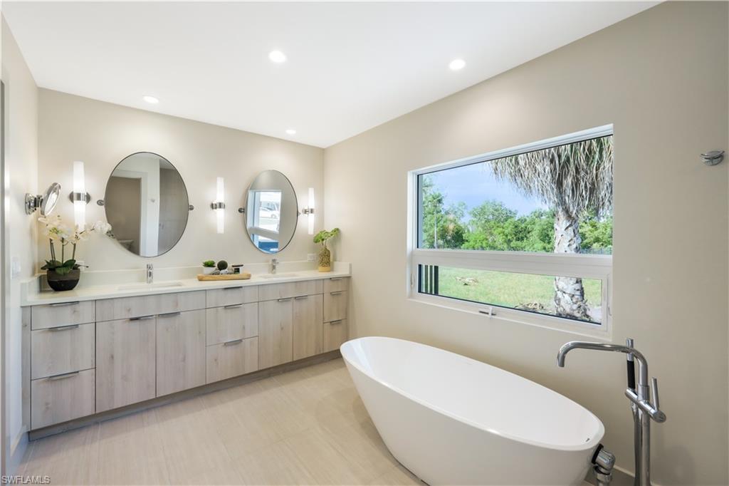 5215 Seashell Avenue Naples, FL 34103 - Photo 18 of 47 a bathroom with a granite countertop sink mirror and bathtub