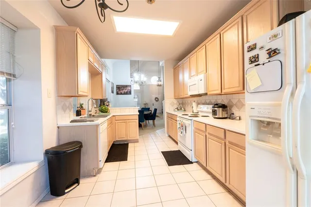 a large white kitchen with cabinets a sink a window and white appliances