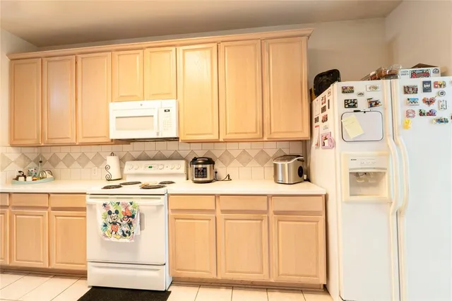 a kitchen with a refrigerator a stove a sink and white cabinets
