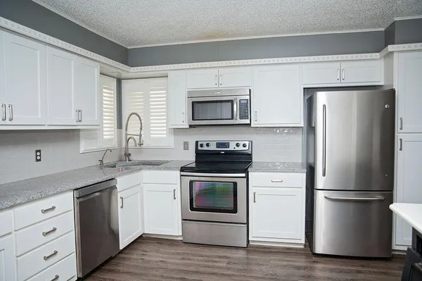 a kitchen with white cabinets stainless steel appliances and a window