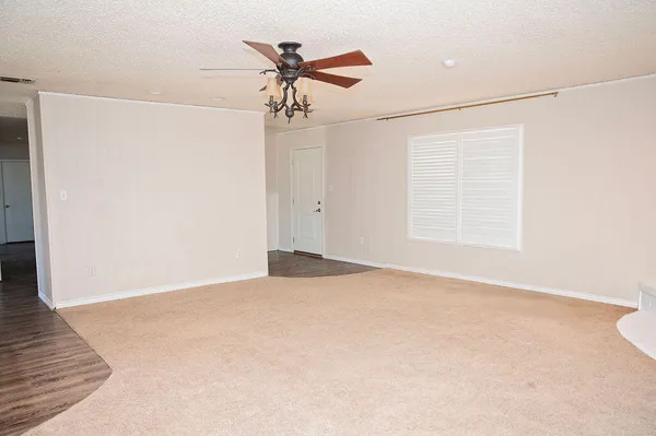 an empty room with a chandelier fan and windows
