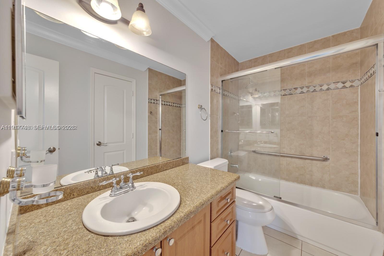 815 Northwest 126th Court Miami, FL 33182 - Photo 16 of 20 a bathroom with a granite countertop sink a mirror and a bathtub