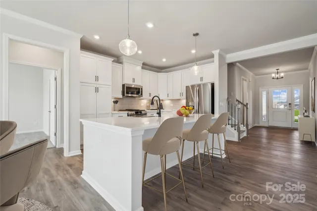 a kitchen with stainless steel appliances kitchen island granite countertop a stove a refrigerator a sink a dining table and chairs with wooden floor