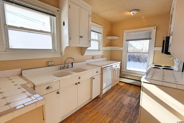 a kitchen with a sink appliances wooden floor and a window