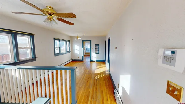 a view of a hallway with wooden floor and a ceiling fan