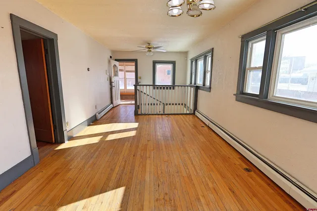 an empty room with wooden floor and windows