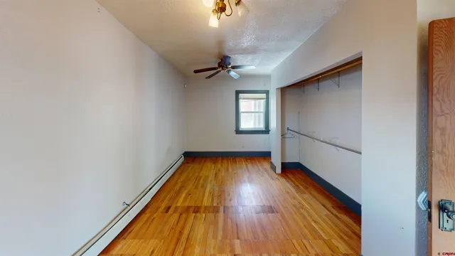 a view of a room with wooden floor staircase and a ceiling fan