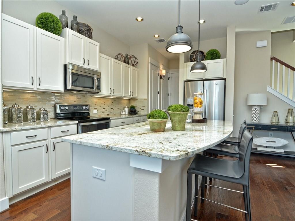 12504 Red Sparrow Street, Unit 1 Austin, TX 78729 - Photo 11 of 22 a kitchen with stainless steel appliances granite countertop a sink dishwasher a stove a microwave oven and a dining table with wooden floor