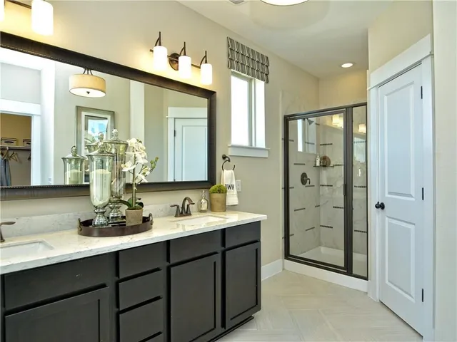 a bathroom with a double vanity sink mirror and shower