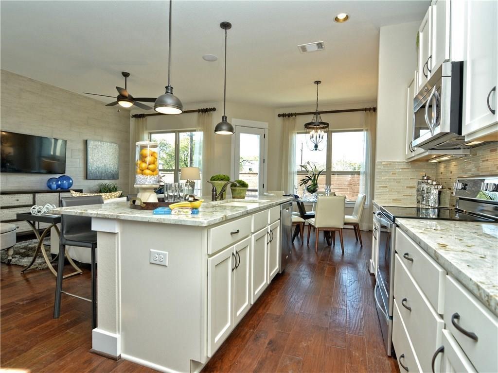 12504 Red Sparrow Street, Unit 1 Austin, TX 78729 - Photo 10 of 22 a kitchen with stainless steel appliances granite countertop a stove top oven a sink a dining table and chairs with wooden floor