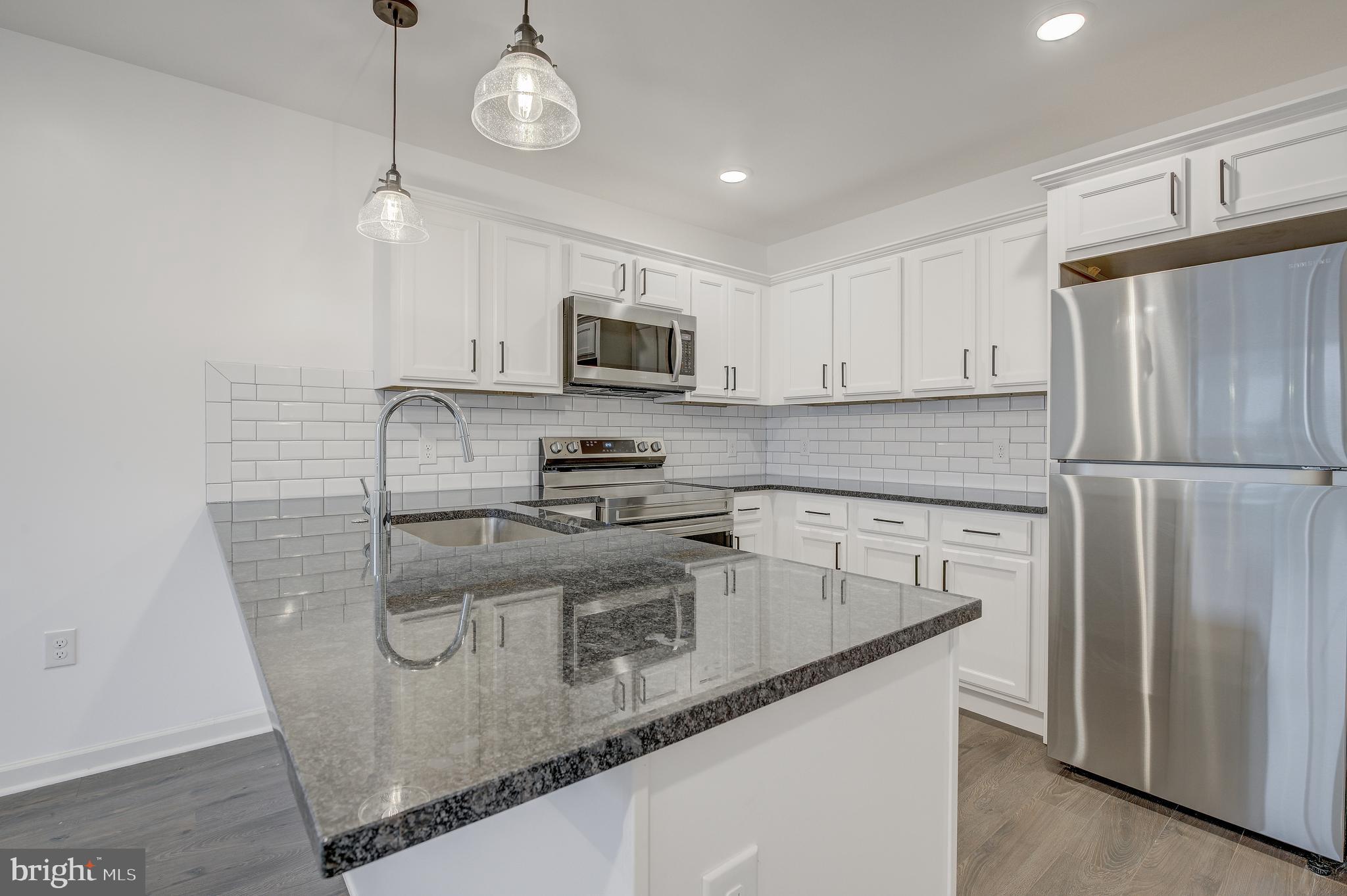 6649 Ridge Avenue, Unit C207 Philadelphia, PA 19128 - Photo 1 of 10 a kitchen with stainless steel appliances granite countertop a refrigerator a stove a sink and a microwave