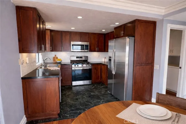 a kitchen with stainless steel appliances granite countertop a refrigerator a stove top oven a sink and dishwasher