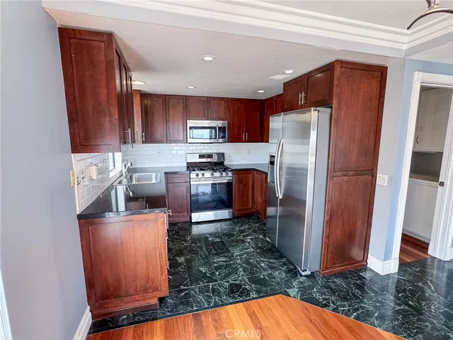 a kitchen with stainless steel appliances granite countertop a refrigerator a stove top oven a sink and dishwasher