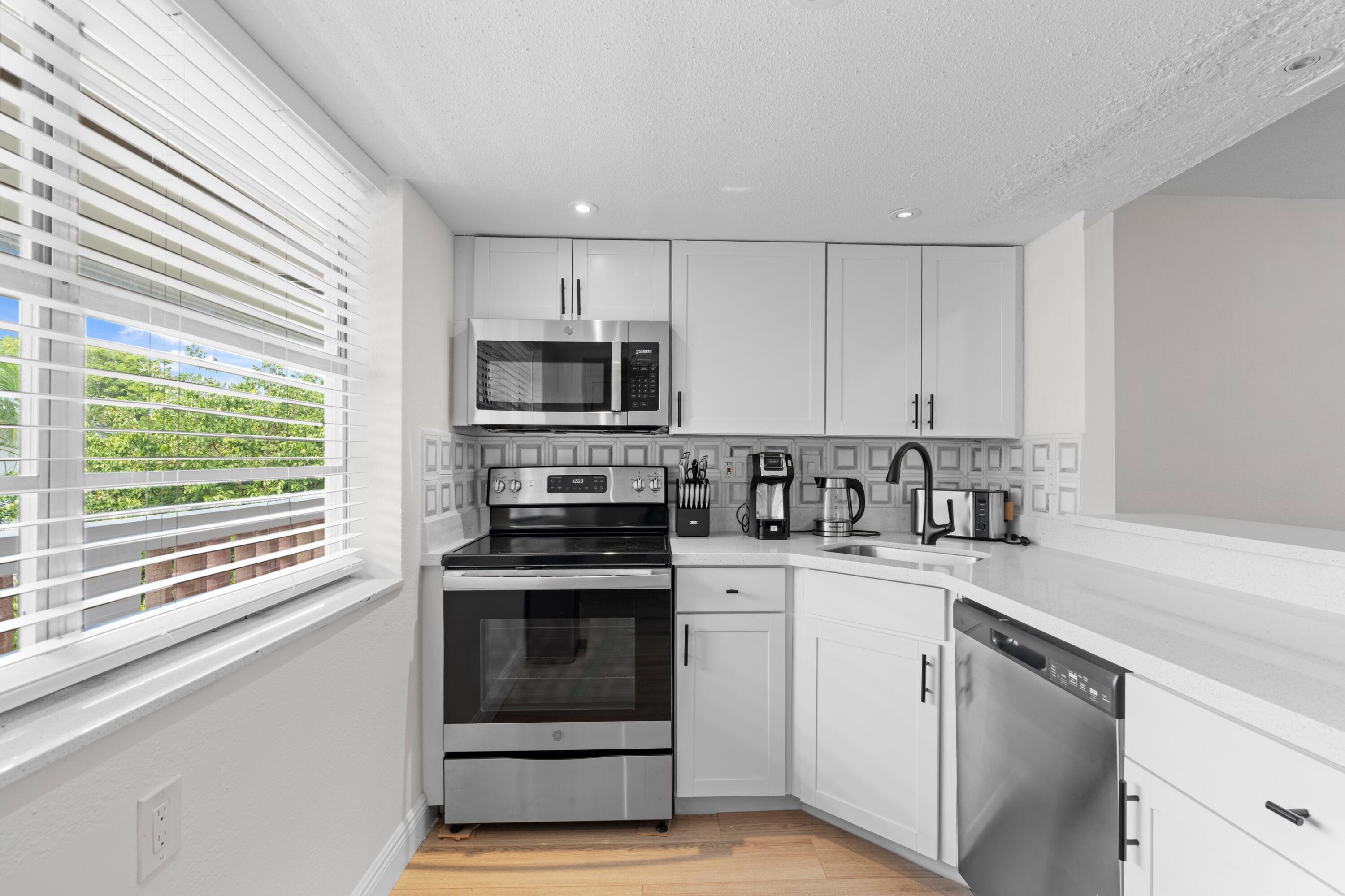 40 Southeast 13th Street, Unit B1 Boca Raton, FL 33432 - Photo 9 of 34 a kitchen with stainless steel appliances granite countertop white cabinets a sink a stove a microwave and a refrigerator