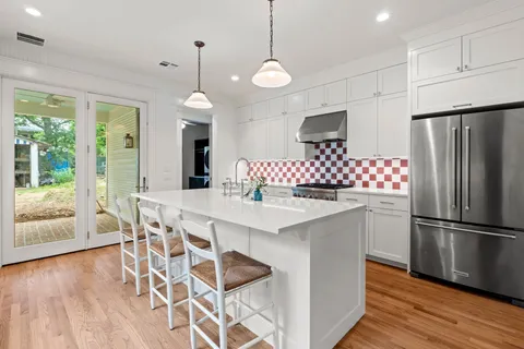 a kitchen with stainless steel appliances granite countertop a refrigerator a sink a stove a dining table and chairs