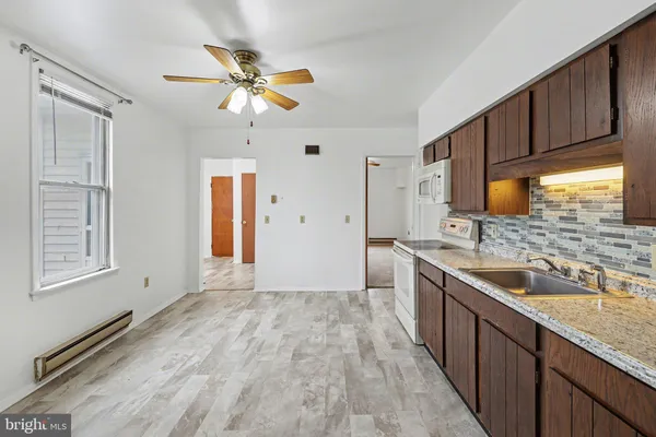 a kitchen with stainless steel appliances granite countertop a sink cabinets wooden floor and a window