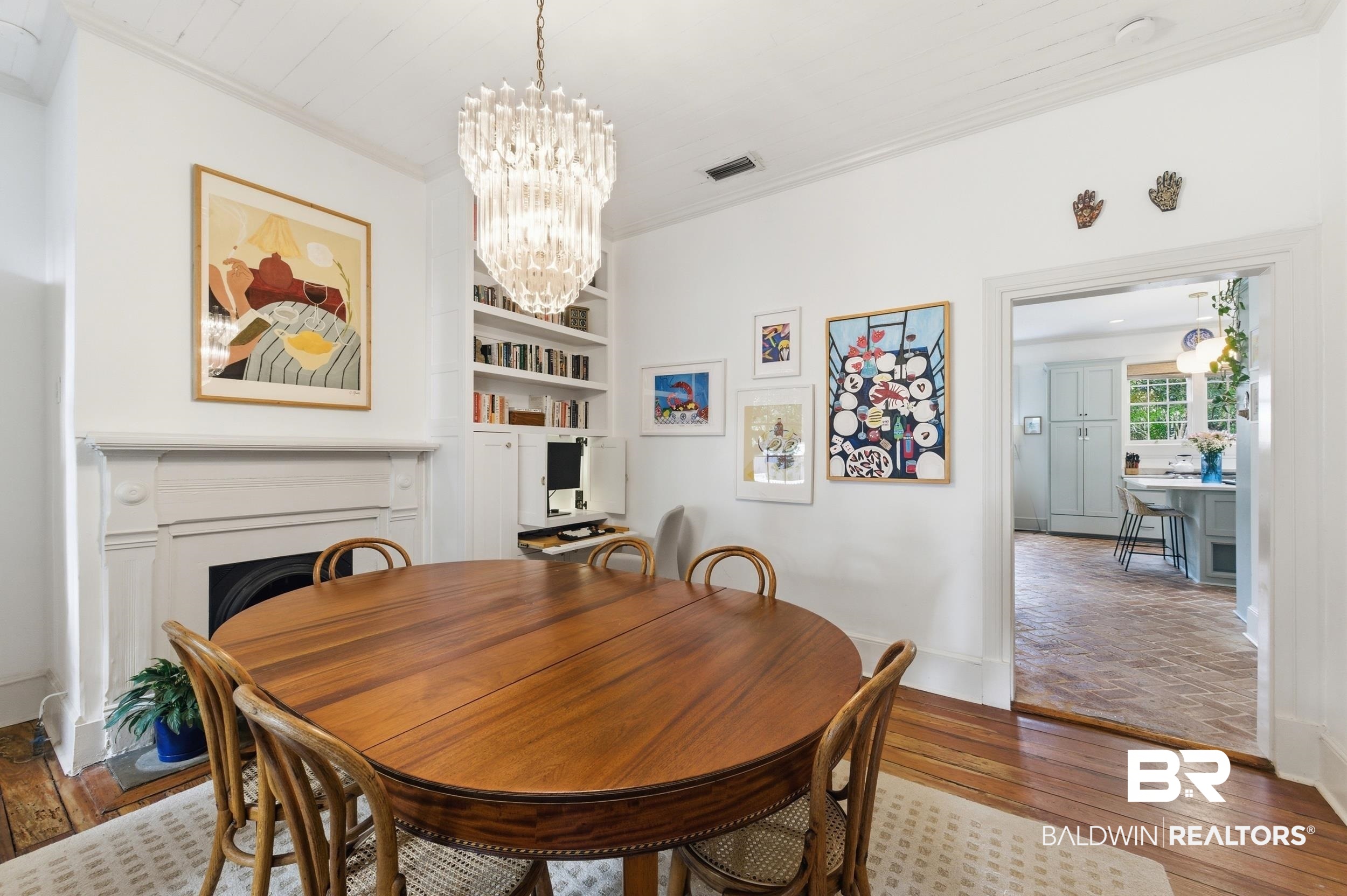 350 Charles Street Mobile, AL 36604 - Photo 15 of 52 Dining area featuring a decorative fireplace with a substantial mantel, built-in shelving, a prominent crystal chandelier, and wood flooring