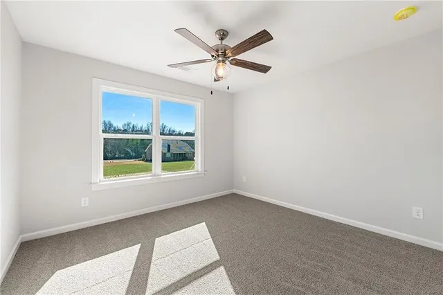 an empty room with ceiling fan and windows