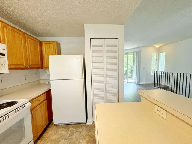 a kitchen with a refrigerator a stove a washer dryer and white cabinets
