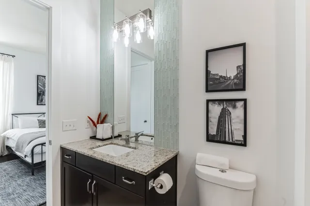a bathroom with a granite countertop sink a toilet and a mirror