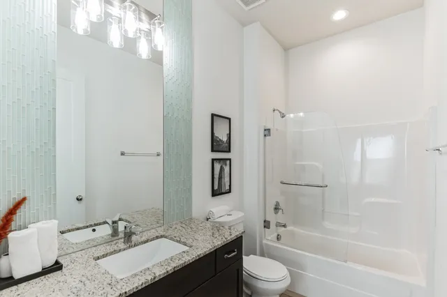 a bathroom with a granite countertop tub sink toilet and mirror