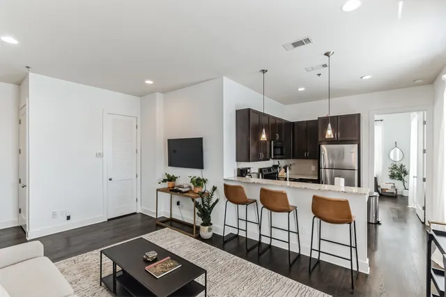 a living room with furniture a flat screen tv and kitchen view