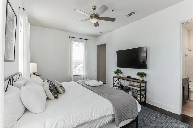a bedroom with a bed tv on table and a window
