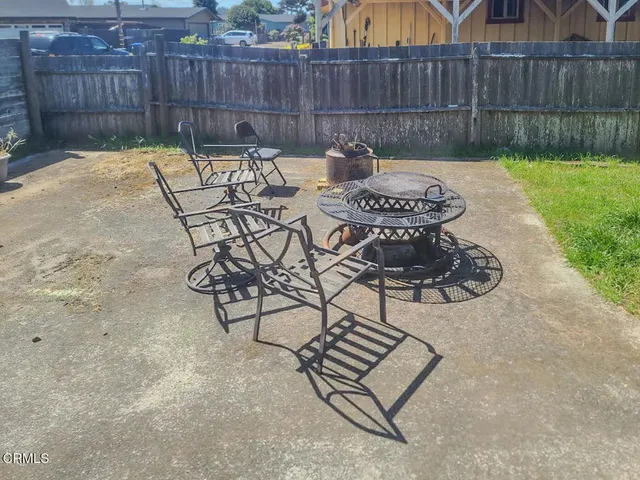 a view of a backyard with table and chairs potted plants and wooden fence