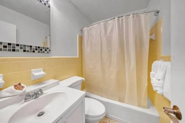 a bathroom with a sink a toilet and shower curtain