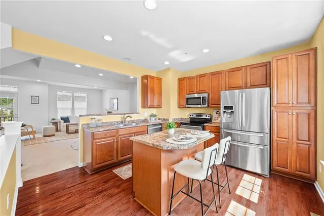 a kitchen with stainless steel appliances granite countertop a refrigerator a stove top oven a sink dishwasher and wooden cabinets with wooden floor