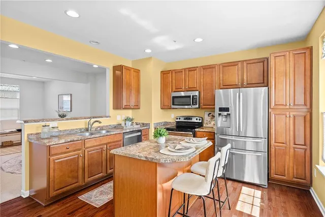 a kitchen with a refrigerator a stove top oven a sink and dishwasher with wooden floor