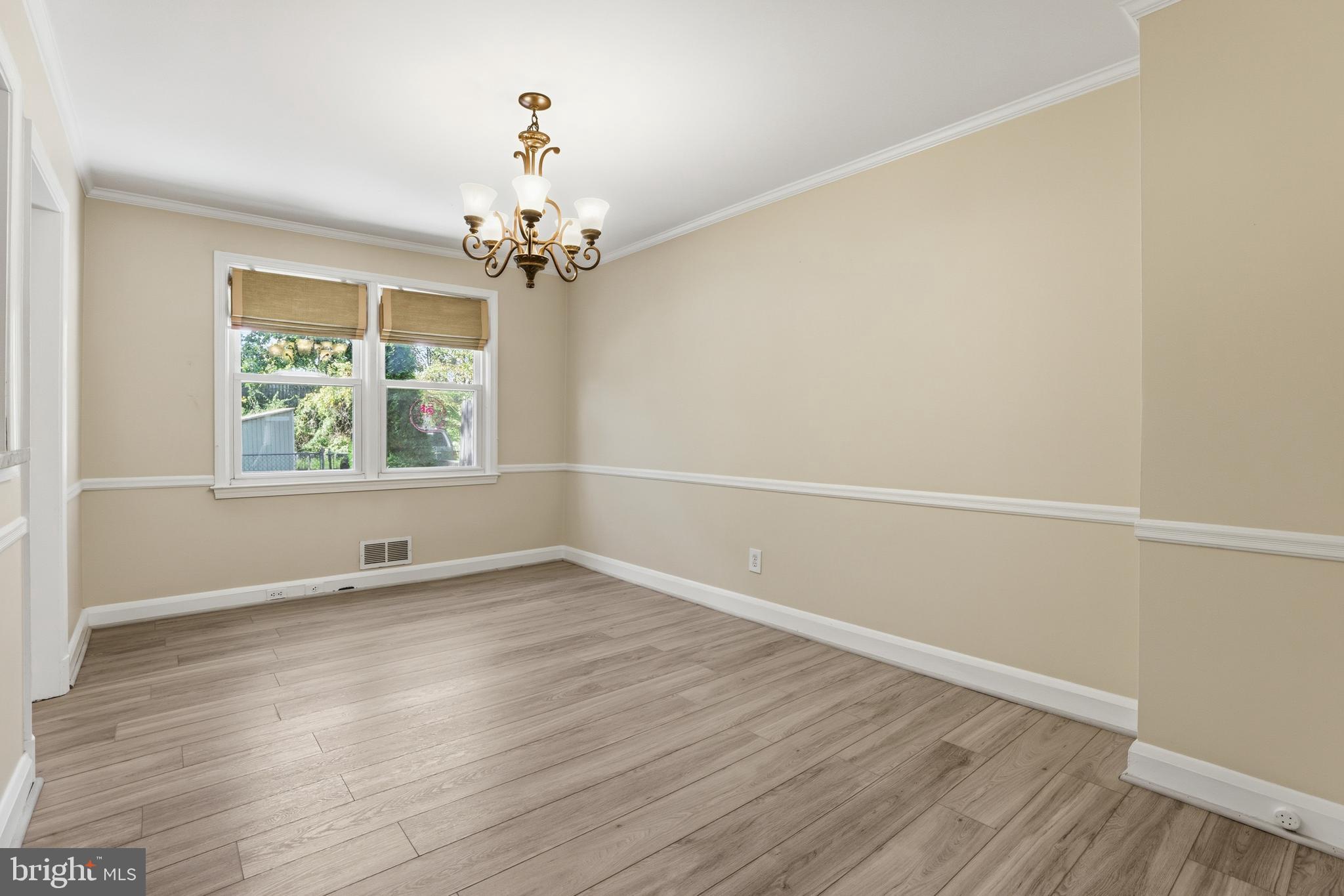 1002 Winsford Road Baltimore, MD 21204 - Photo 8 of 30 an empty room with wooden floor chandelier and windows