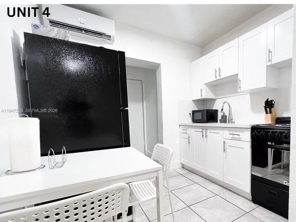 a kitchen with stainless steel appliances granite countertop a refrigerator a sink a stove and white cabinets