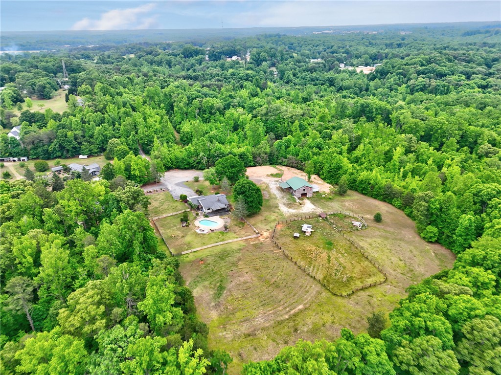 433 Latham Road Easley, SC 29640 - Photo 33 of 50 An aerial perspective reveals a secluded estate featuring a private pool, barn, and extensive acreage, all embraced by dense woodlands.