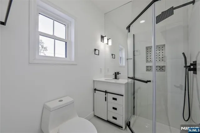 a bathroom with a toilet sink vanity and shower