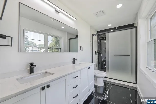 a bathroom with a double vanity sink mirror and shower