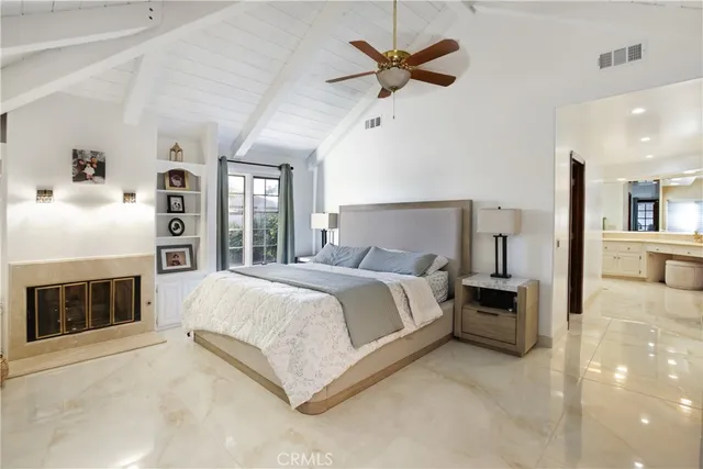 a spacious bedroom with a large bed a chandelier and windows