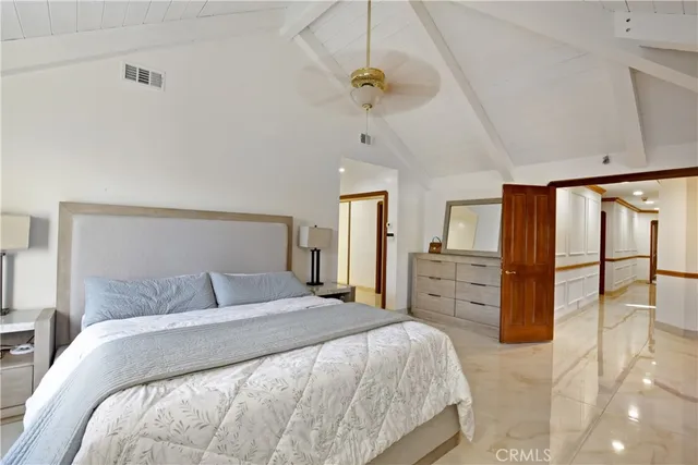 a bedroom with a large bed and ceiling fan