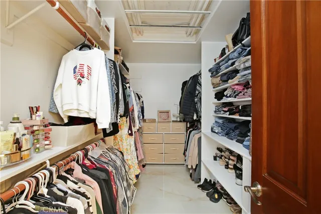 a view of walk in closet with clothes and shoes