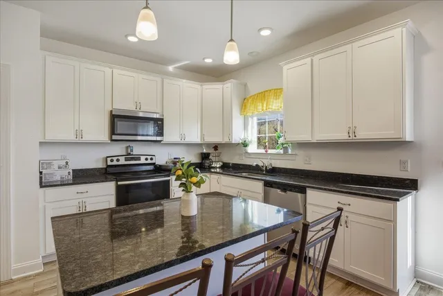 a kitchen with stainless steel appliances granite countertop a stove a sink a microwave a center island and cabinets