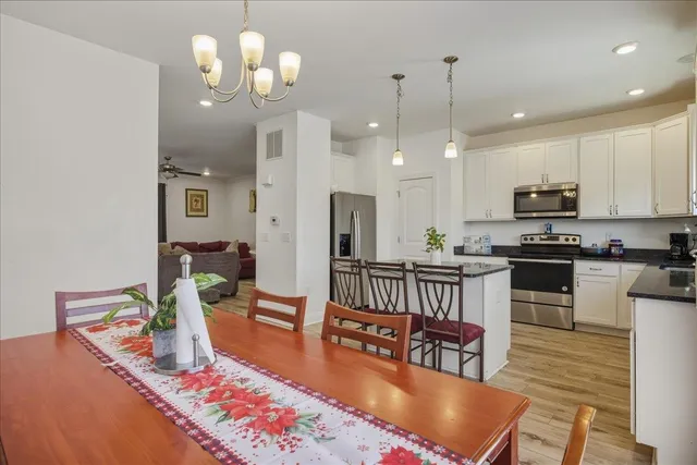 a large kitchen with kitchen island stainless steel appliances a stove center island a dining table and chairs