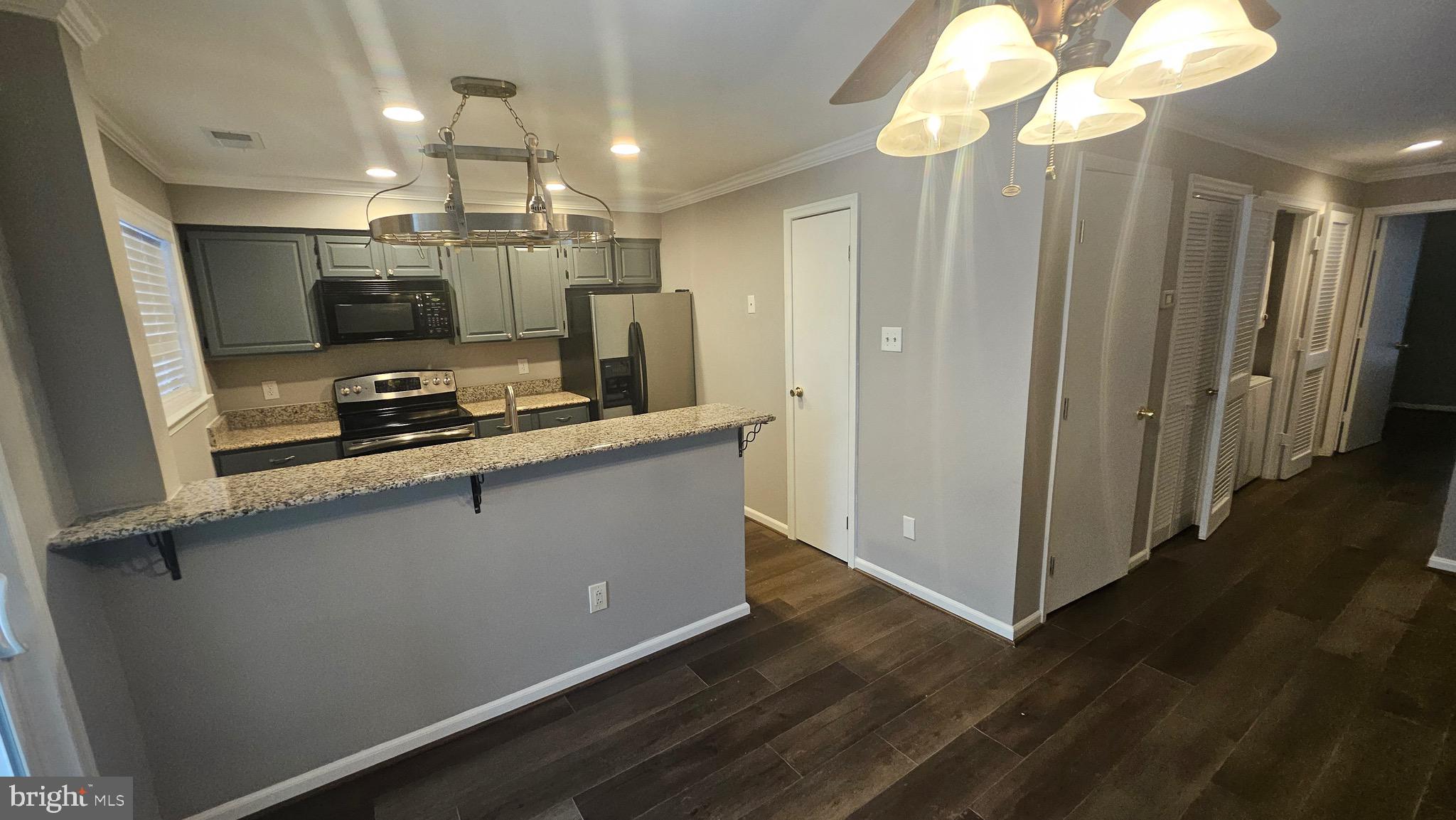 14224 Jib Street, Unit 6142 Laurel, MD 20707 - Photo 4 of 15 a kitchen with stainless steel appliances a refrigerator a sink dishwasher a stove and a dining table with wooden floor