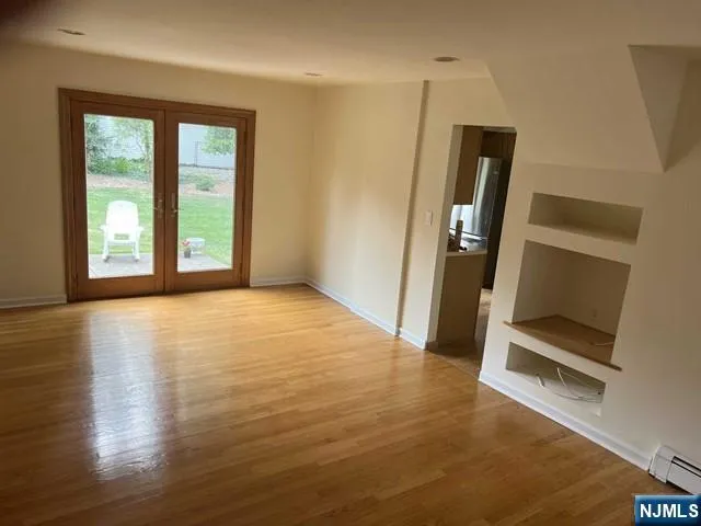 a view of empty room with window and wooden floor