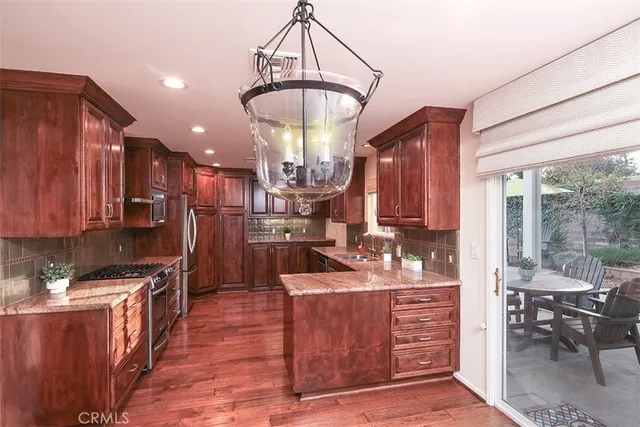 a kitchen with kitchen island granite countertop wooden cabinets a sink and dishwasher with wooden floor