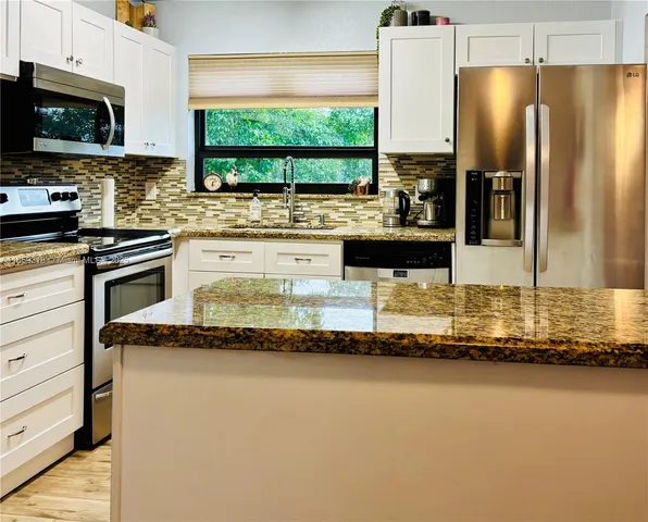 a kitchen with stainless steel appliances granite countertop a sink a stove and a refrigerator