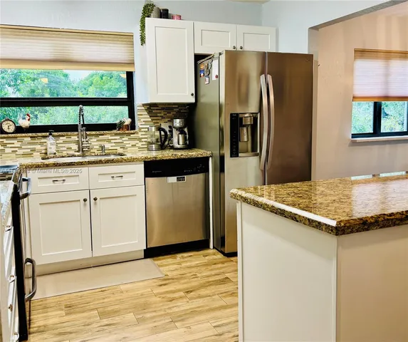 a kitchen with granite countertop white cabinets and refrigerator