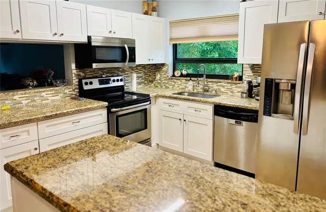 a kitchen with stainless steel appliances granite countertop a stove a sink and a microwave
